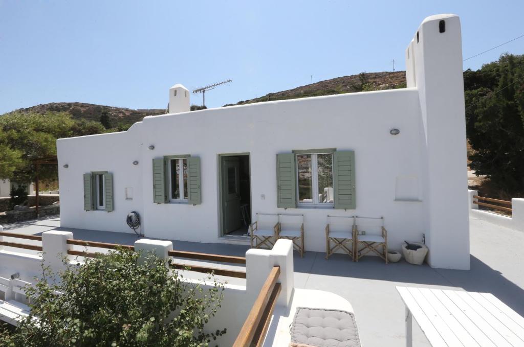 a white house with green shutters and a patio at Onverra Villa in Rózia