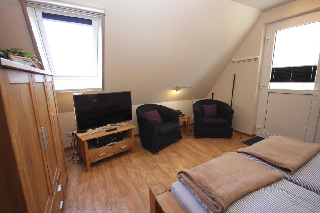 - une chambre avec un lit, deux chaises et une télévision dans l'établissement Appartement Bianca, à Wustrow