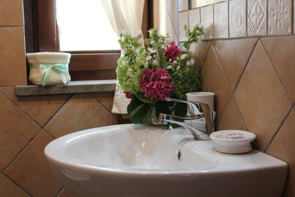 un lavandino in bagno con un vaso di fiori sopra di B&B La Casa della Nonna a Viterbo