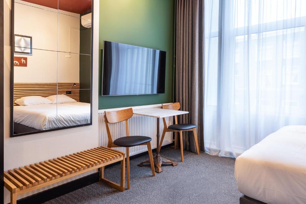 ein Hotelzimmer mit einem Tisch, 2 Stühlen und einem TV in der Unterkunft Weber Hotel in Amsterdam