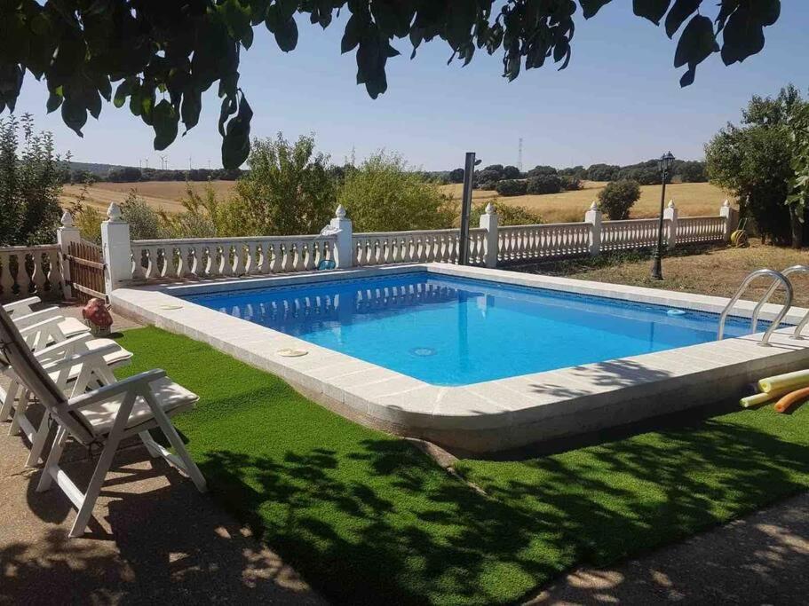 a swimming pool in a yard with two chairs at Villa rural de campo aldea Las Zorizas in Munera