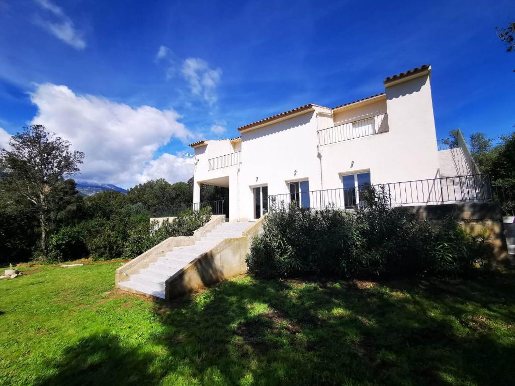 uma grande casa branca com escadas num quintal em Casa Sognu di Orizonte em Figari