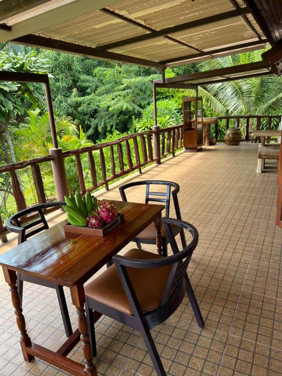 a wooden table and chairs on a deck at Traditional Thai house บ้านเรือนไทย ใกล้หาดระยอง in Ban Chak Phai