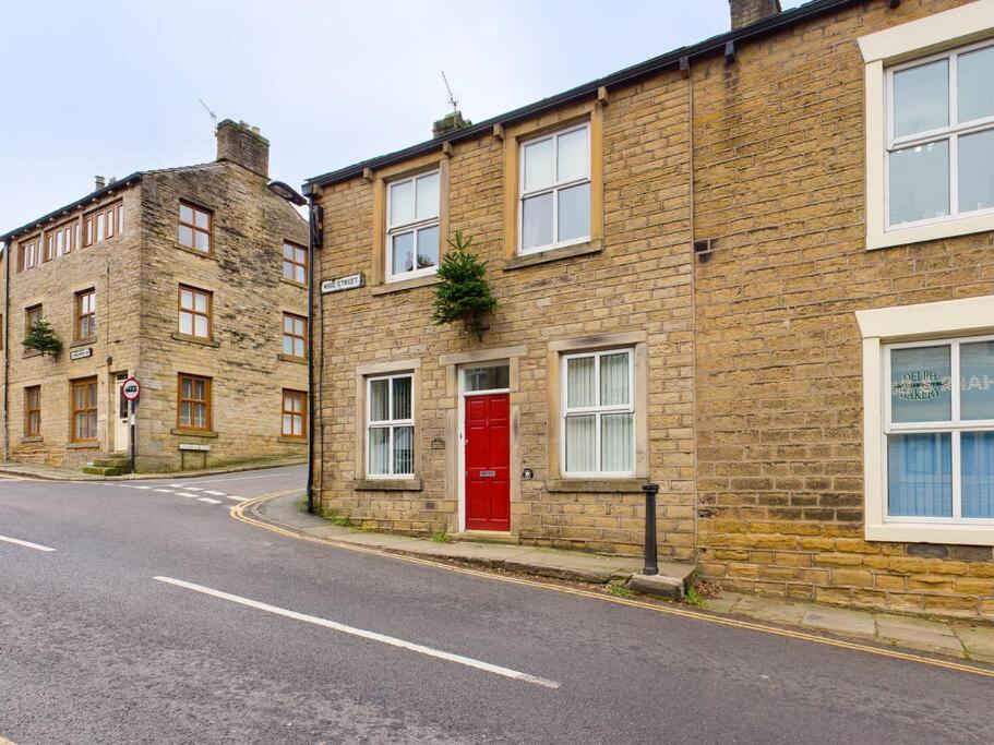un edificio de ladrillo con una puerta roja en una calle en 1 King Street Accommodation, en Delph