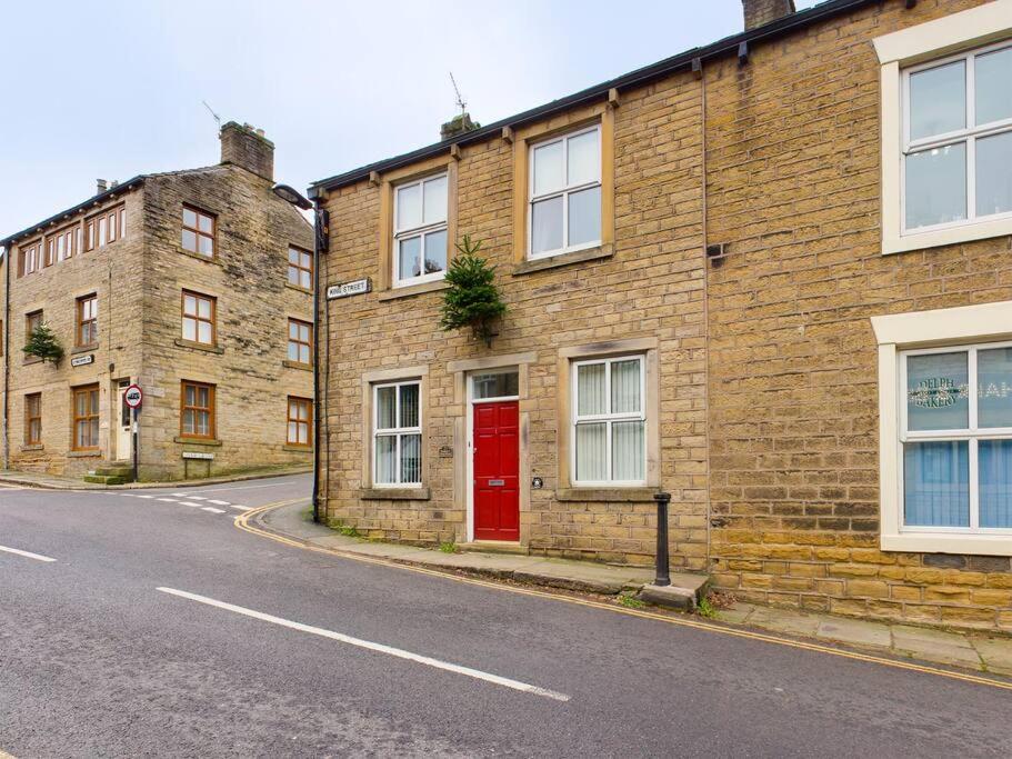 a brick building with a red door on a street at 1 King Street Accommodation in Delph