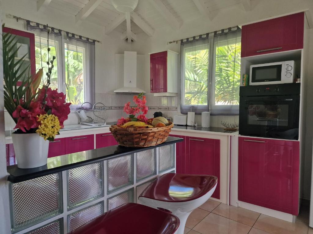 une cuisine avec des placards rouges et une corbeille de fruits sur un comptoir dans l'établissement Les Villas de Boisvin, à Le Moule