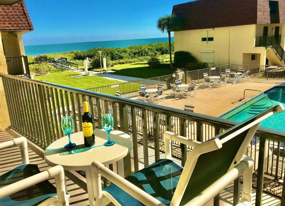 balcón con mesa y 2 copas de vino en Condo By The Sea! en Cocoa Beach