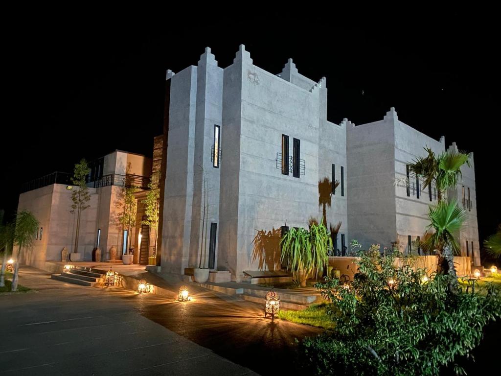 un bâtiment blanc avec des lumières devant lui la nuit dans l'établissement Villa Malaa'ika, à Marrakech