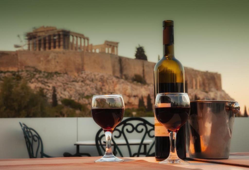 Una botella de vino y dos copas en una mesa. en Acropolis View Hotel, en Atenas