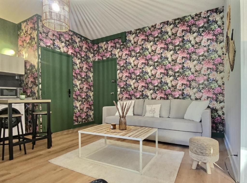 uma sala de estar com um sofá e uma parede floral em Cosy Break Jardins des plantes em Le Mans