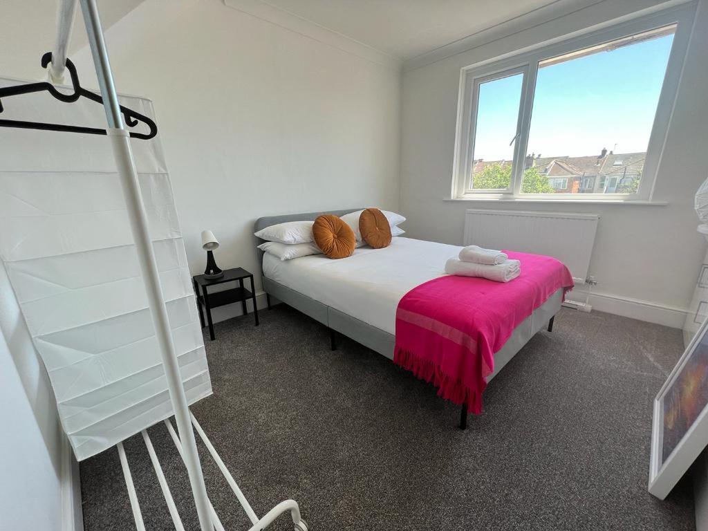 a bedroom with a bed with a pink blanket and a window at 2 Br Flat Free Parking Great Location in Southampton