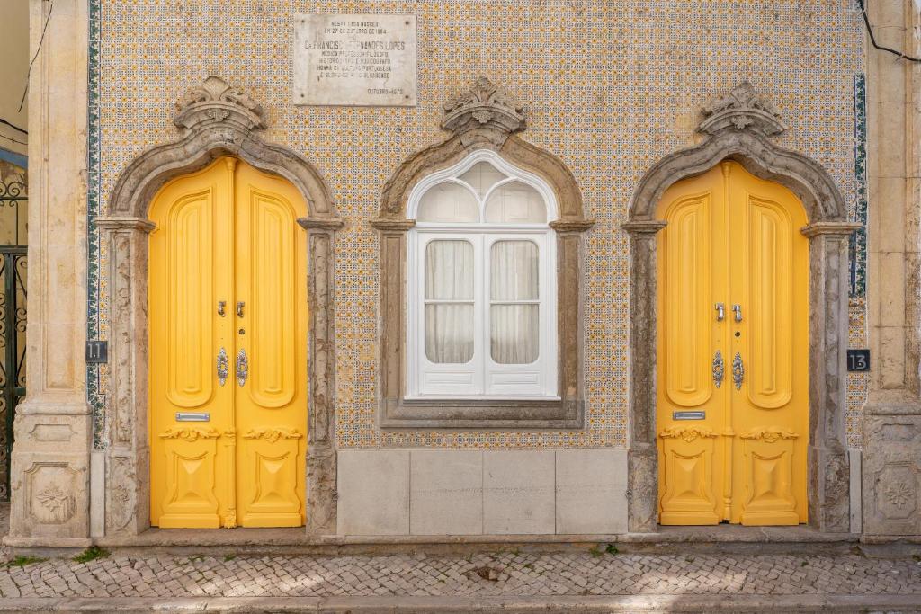twee gele deuren en een raam op een gebouw bij Town House Olhão 11 in Olhão