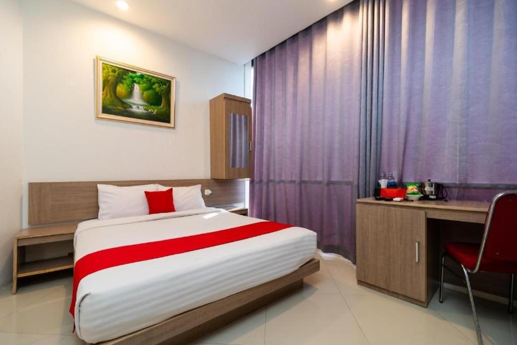 a hotel room with a bed and a desk and a chair at Hotel Domino in Palembang