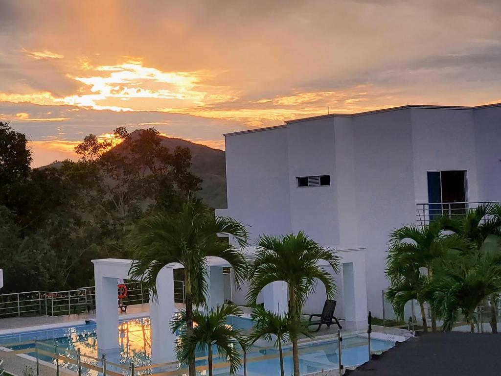 a building with a pool and palm trees in front of a sunset at Ibiza Reservado 201 in Melgar