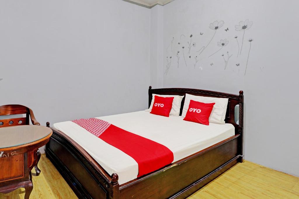 Un dormitorio con una cama con almohadas rojas y una mesa. en OYO 2452 Hotel Metro en Bandung