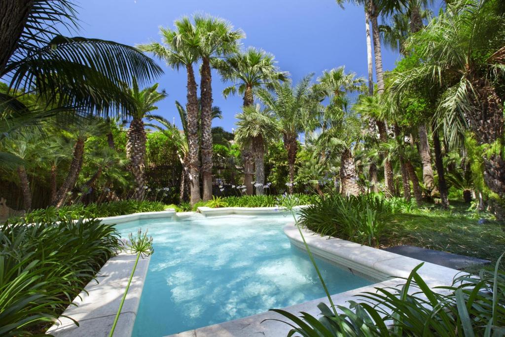 einen Pool in einem Garten mit Palmen in der Unterkunft Estate4home- Villa Le Camelie in Sant'Agnello