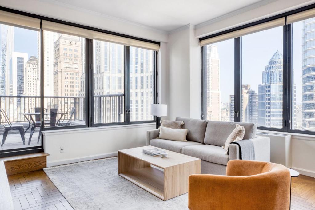 a living room with a couch and chairs and large windows at Midtown East 3BR w Doorman Gym nr Bloomingdales NYC-915 in New York