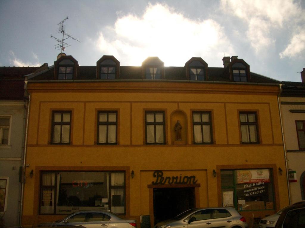 a yellow building with cars parked in front of it at Penzion u Antonicka in Prostějov