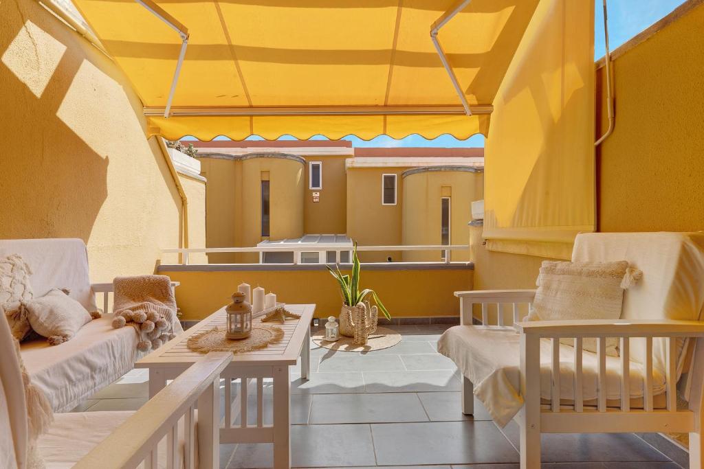 d'un balcon avec des chaises, une table et un toit jaune. dans l'établissement Moderno Triplex Sonneland, à Maspalomas