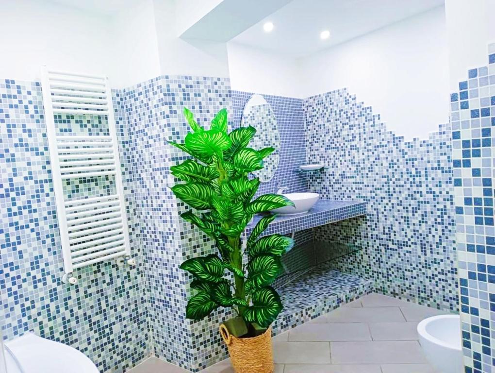 ナポリにあるBORGO LORETO NAPLESの青いタイル張りの壁と植物のあるバスルーム