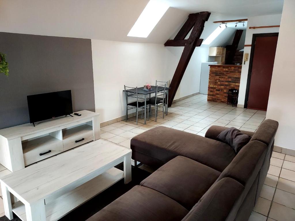 uma sala de estar com um sofá, uma televisão e uma mesa em A 2 pas de la gare em Châlons-en-Champagne