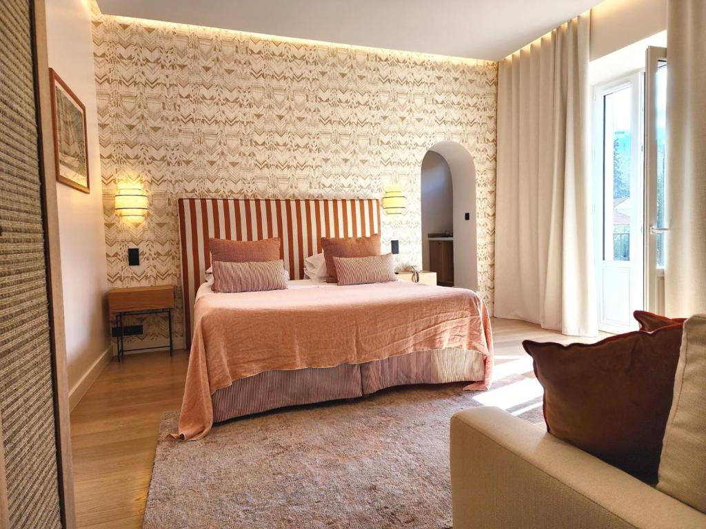 ein Schlafzimmer mit einem großen Bett und einem Sofa in der Unterkunft La Bastide Du Port - Hôtel de Charme in Saint-Tropez
