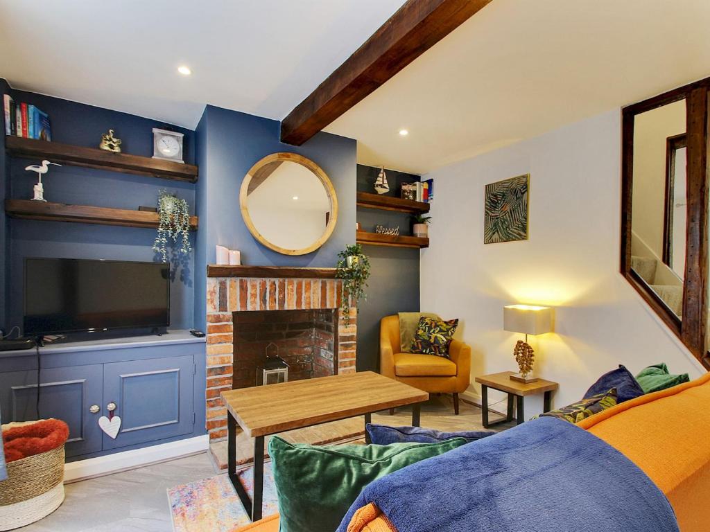 a living room with blue walls and a mirror at Pass the Keys Cosy Cottage Hawkhurst in Cranbrook