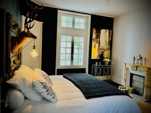 - une chambre avec un lit avec une tête de cerf sur le mur dans l'établissement Domaine de la Croix de Saint Lambert, à Poix-Terron
