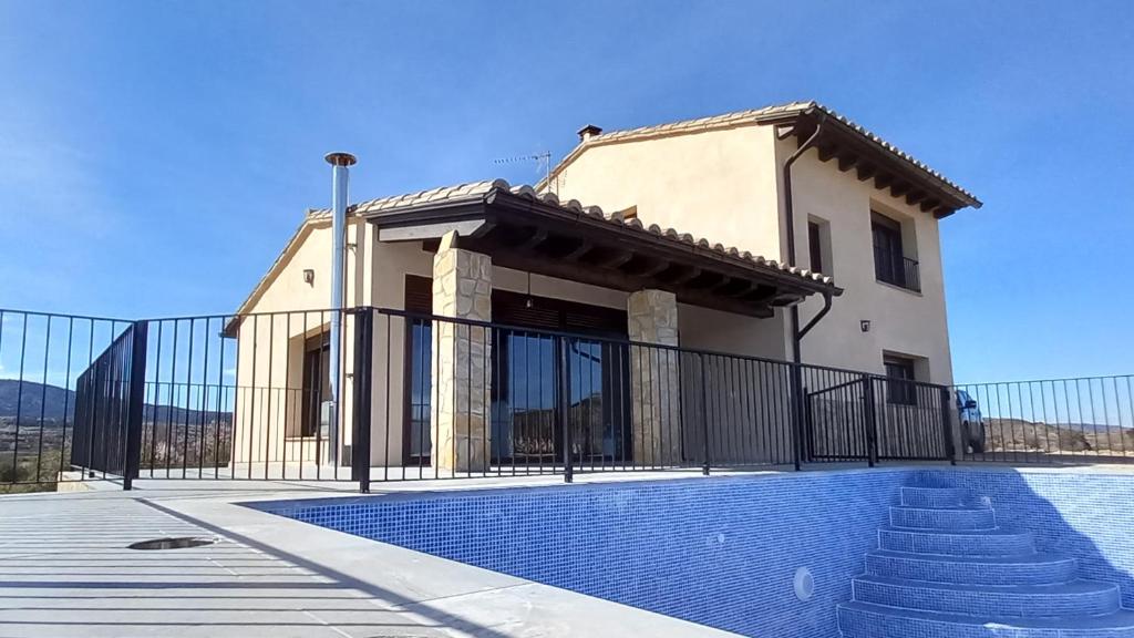 a villa with a swimming pool in front of a house at Casa Rural Raiztruf in Cinctorres
