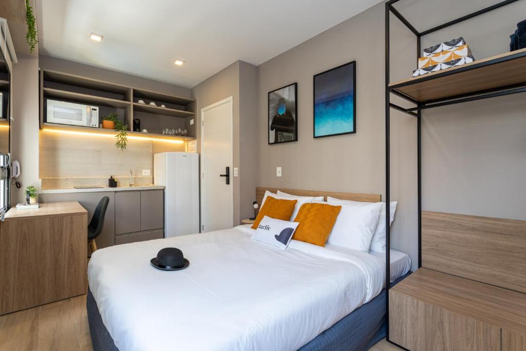 Un dormitorio con una cama grande y una cocina. en Charlie Franca Jardim Paulista, en São Paulo