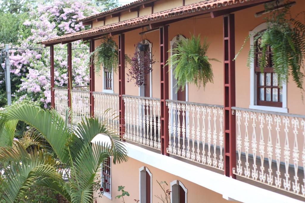 una casa con balcone con alberi da fiore di Recanto das Abelhas - 300 m do centro histórico a Tiradentes