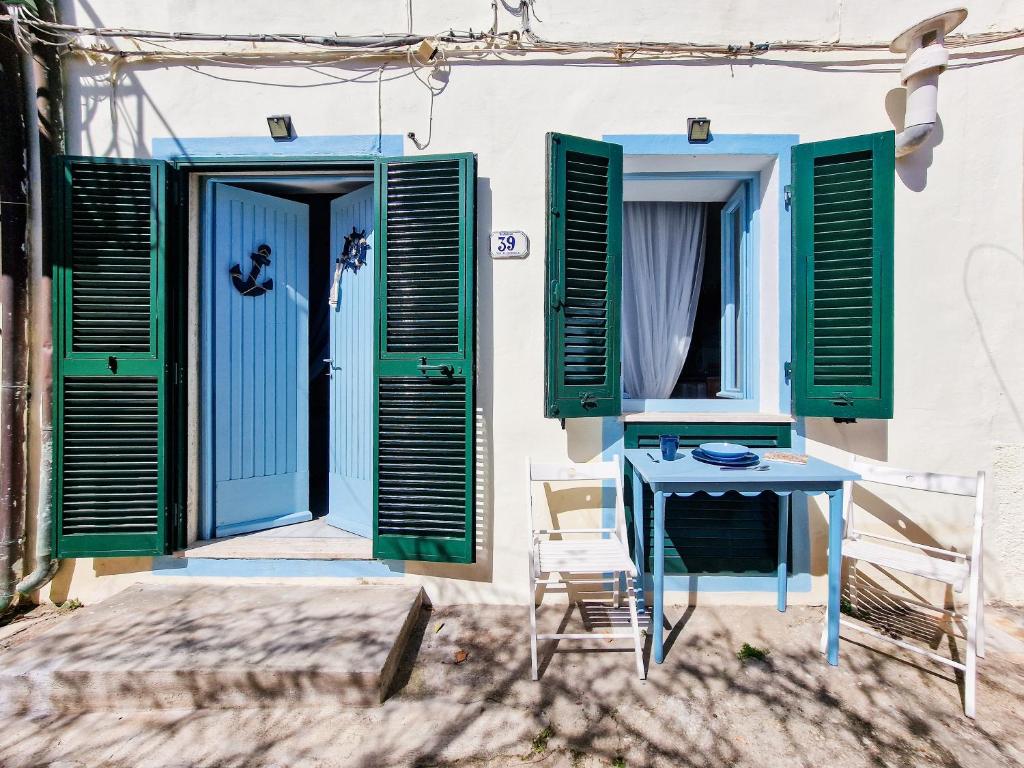 a table and chairs in front of a door with green shutters at Loft Francesca Old City Center in Rio Marina