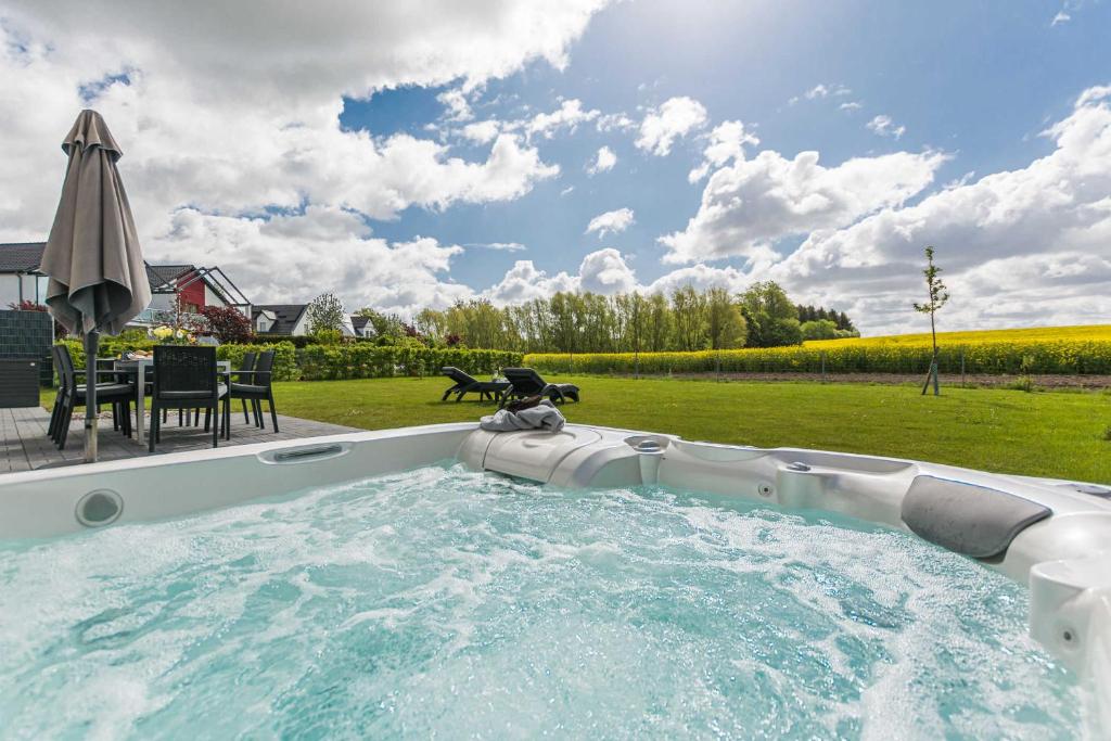 einen Whirlpool im Garten mit einem Tisch und einem Sonnenschirm in der Unterkunft Luxus-Ferien-VILLA AMICI in Göhren-Lebbin