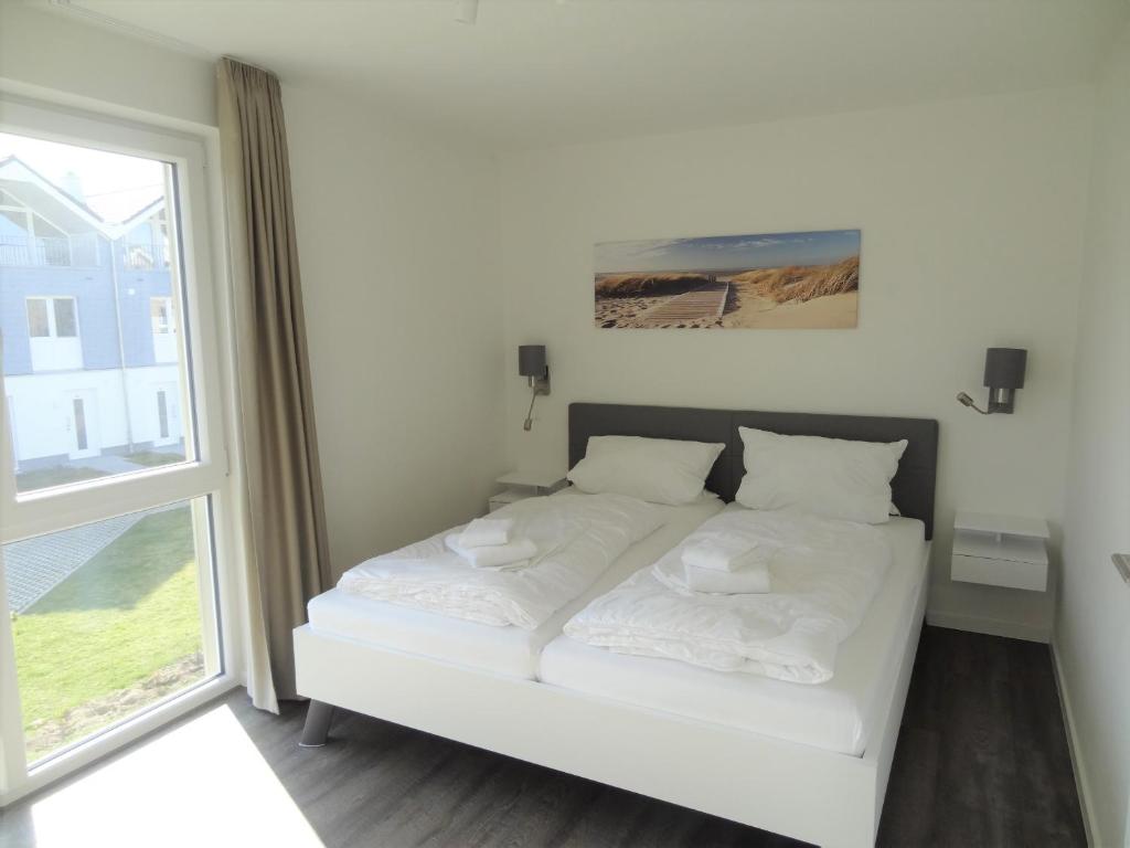 - un lit blanc dans une chambre avec fenêtre dans l'établissement Haus Nr 11, Ferienhaus Fischerhus, à Wangerland