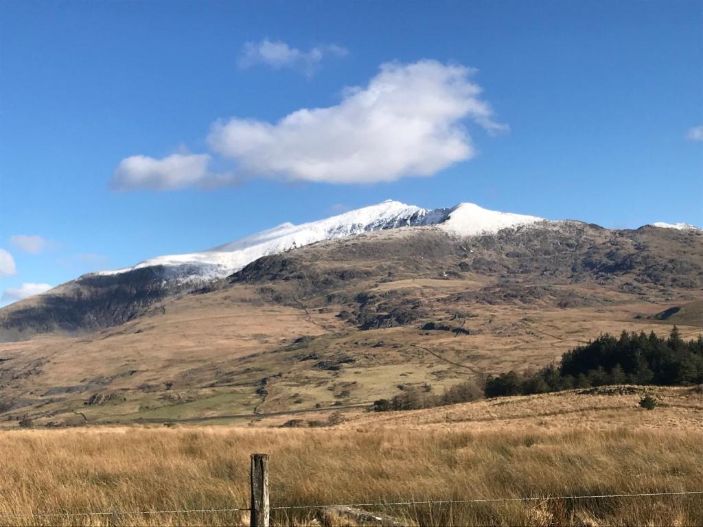 een met sneeuw bedekte berg met een hek op de voorgrond bij Snowdonia Holiday Lodges in Beddgelert