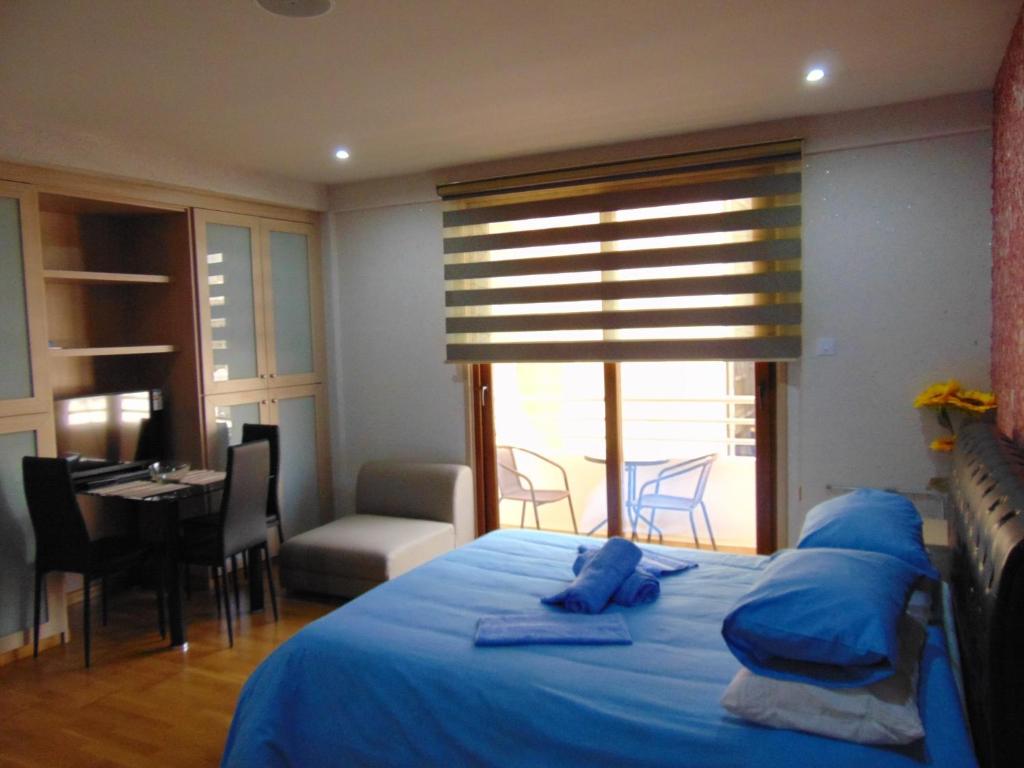 Ithaki Phinikoudes Apartment No. 207 في لارنكا: غرفة نوم بسرير ومخدات زرقاء وطاولة