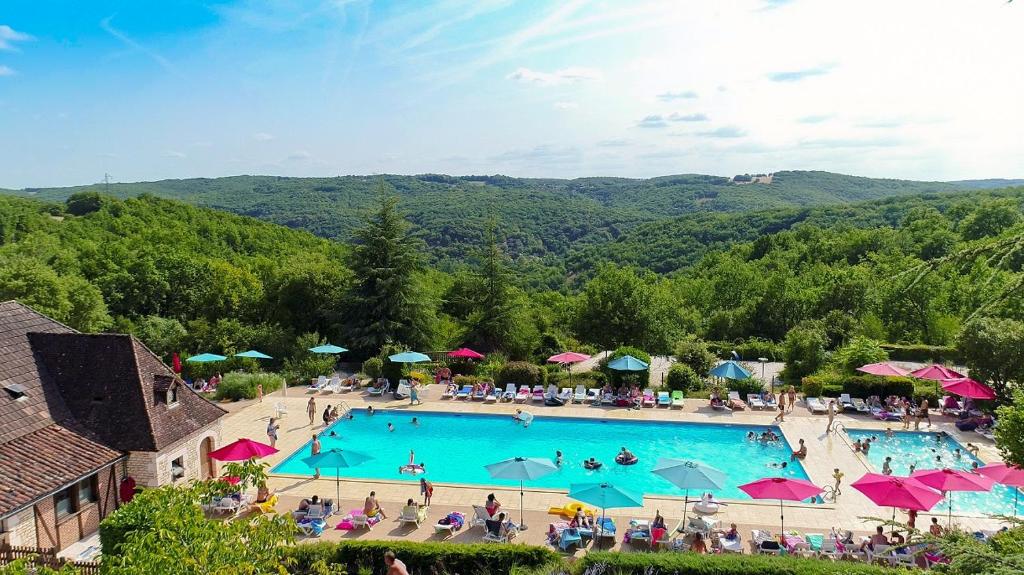 an overhead view of a large swimming pool with people at Camping Domaine de la Paille Basse - Maeva in Souillac