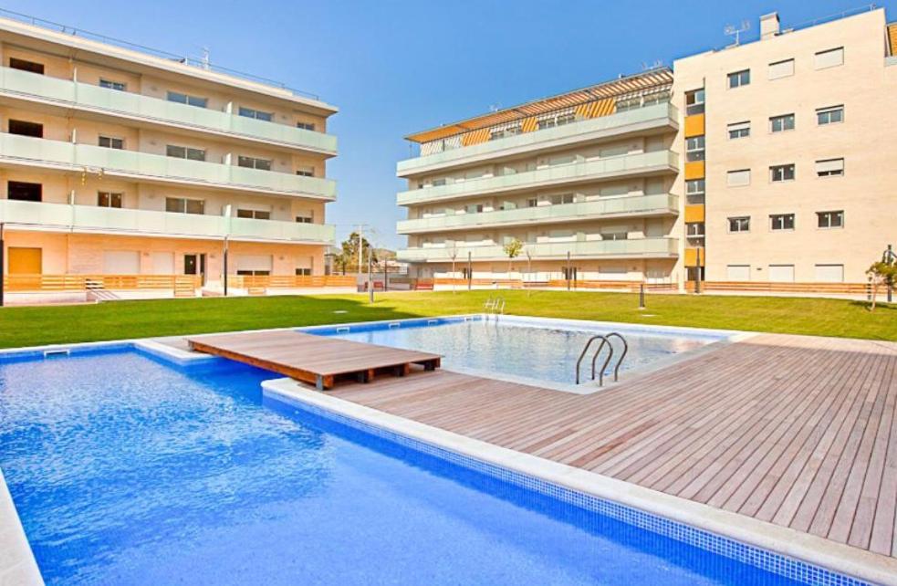 una piscina frente a un edificio en NEW! Apartamento con 2 piscinas, parque infantil, a 1 min de la playa en Sant Antoni de Calonge