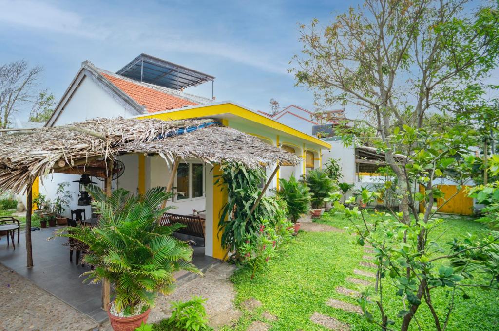 ein gelbes Haus mit Strohdach und Hof in der Unterkunft Be's Beach House An Bang in Hoi An
