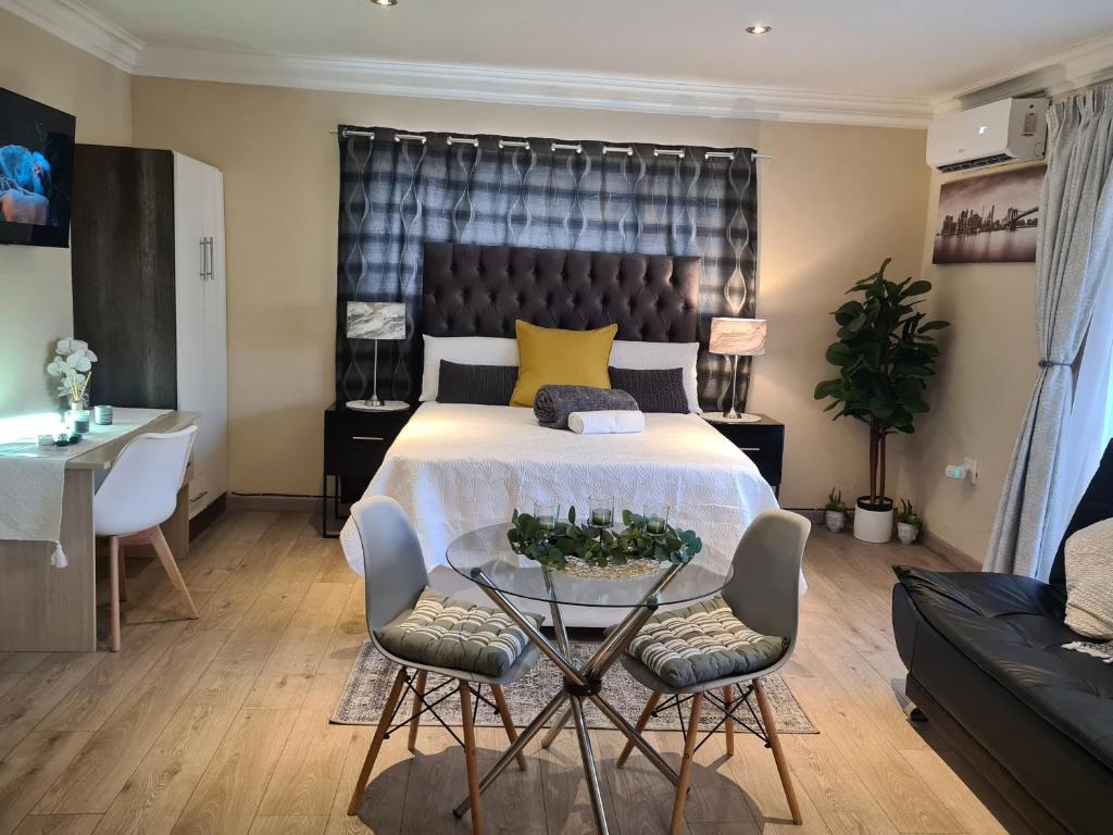 a bedroom with a bed and a table and chairs at Halfway Gardens Home in Midrand