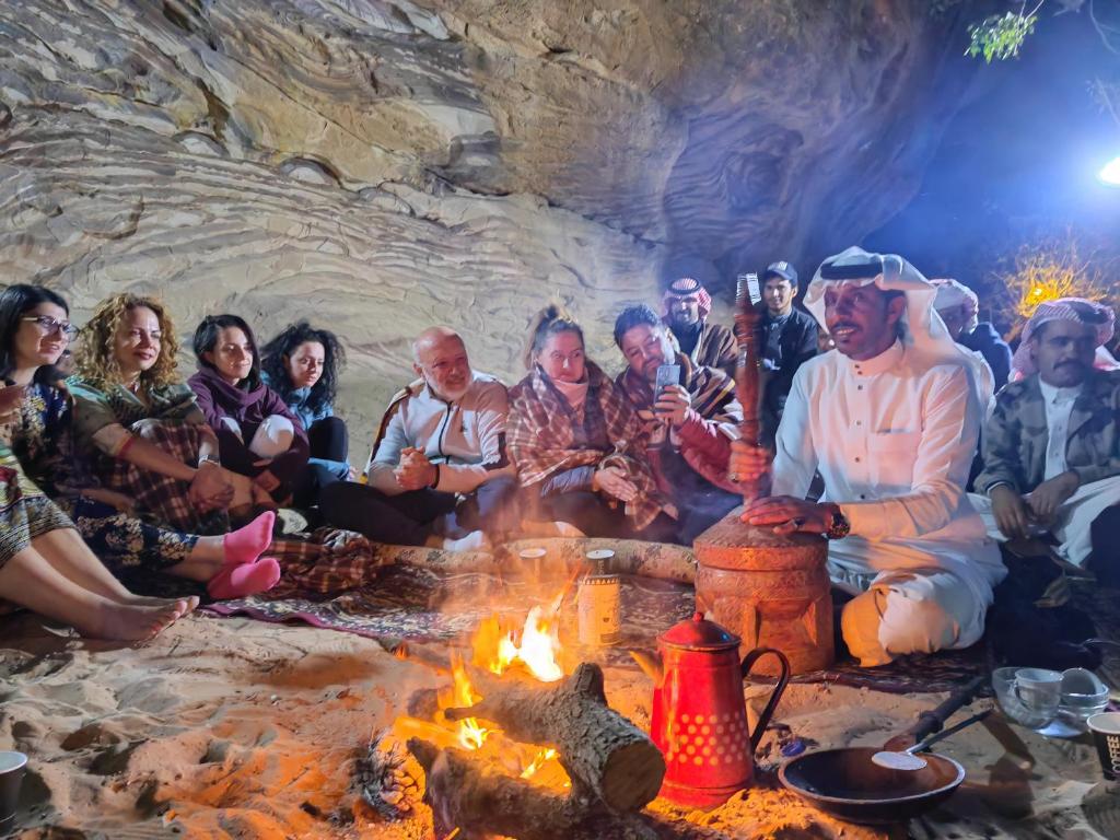 un grupo de personas sentadas alrededor de una fogata en Namla Bedouin Camp en Umm Şawwānah