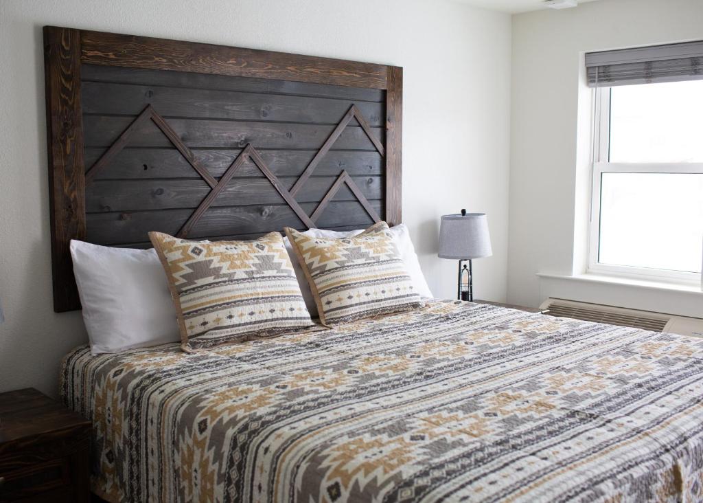 een slaapkamer met een groot bed met een houten hoofdeinde bij Pine Lodge in Encampment