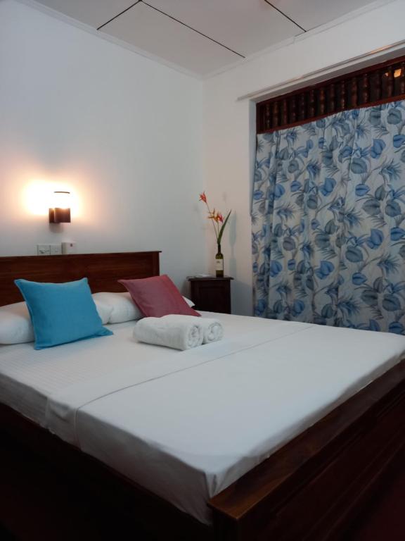 een slaapkamer met een groot wit bed met twee kussens bij Villa Green Garden in Hikkaduwa