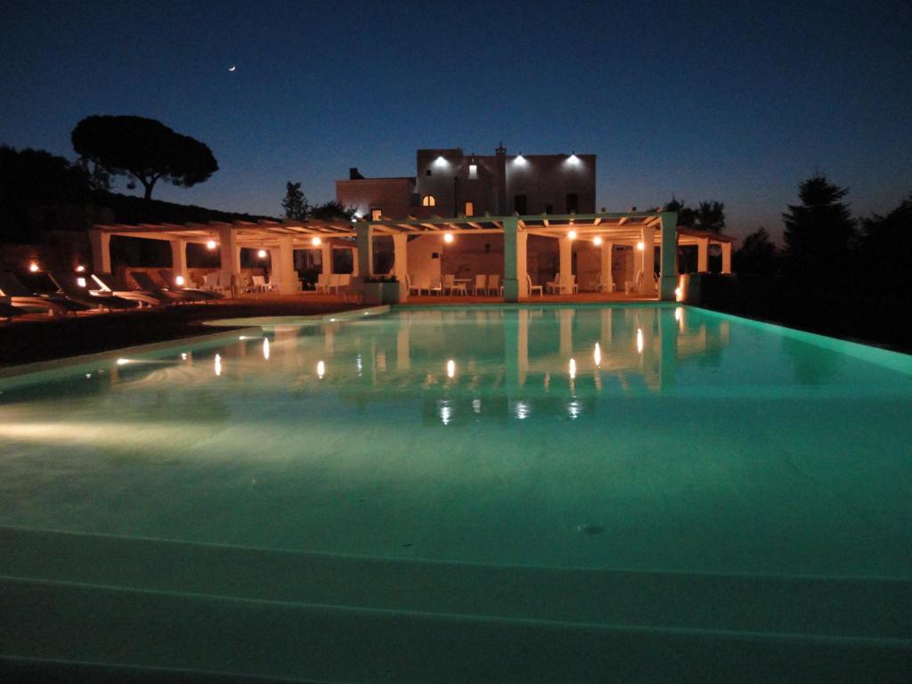 una piscina notturna con una casa sullo sfondo di Masseria Santa Teresa a Monopoli