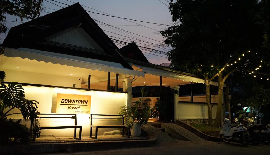 a building with two benches in front of it at Downtown Hostel in Luang Prabang