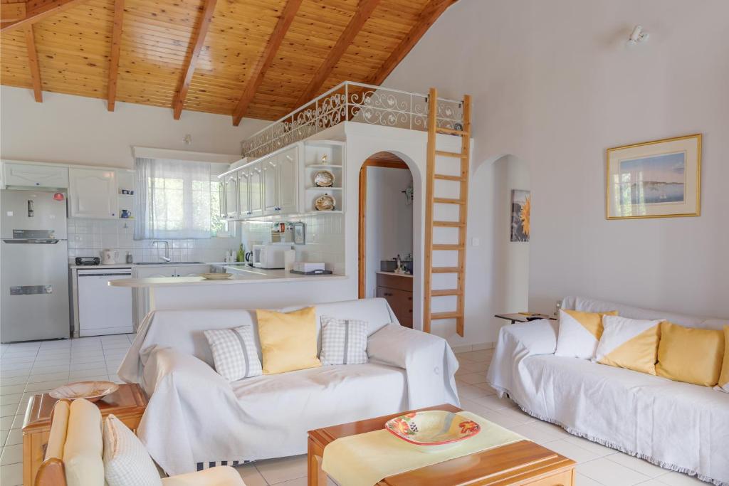 een woonkamer met 2 witte banken en een keuken bij Heliotropio in Kalamaki