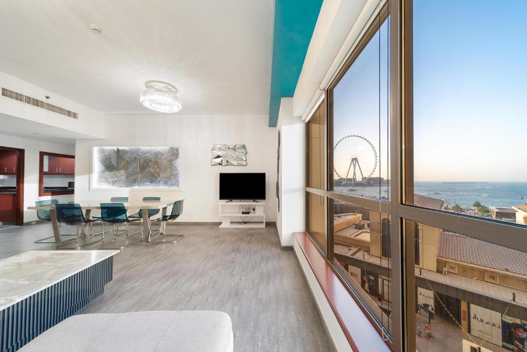 uma sala de estar com uma mesa e uma grande janela em Elan Rimal Suites JBR Beach Sea View no Dubai