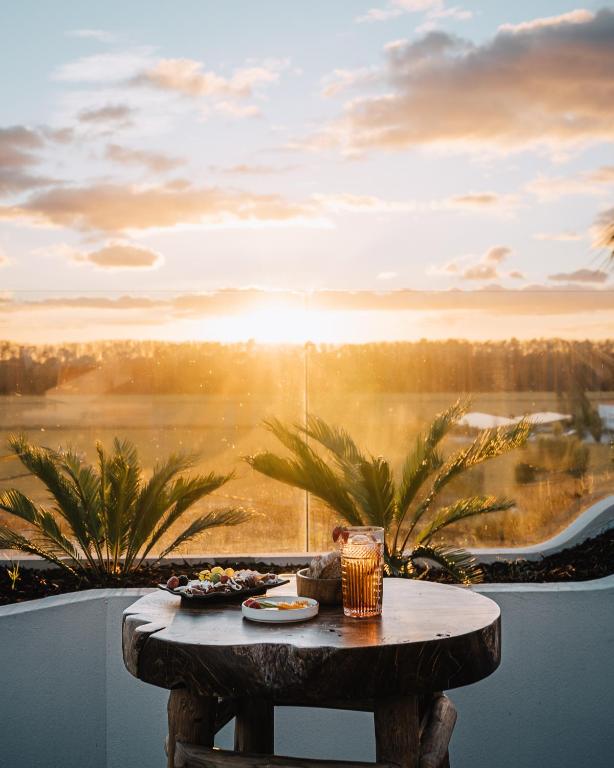 a table on a balcony with a view of the sunset at AlmaLusa Comporta in Comporta