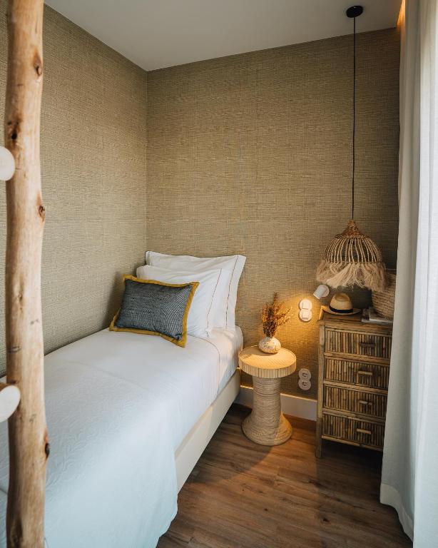 a bedroom with a bed and a side table with a lamp at AlmaLusa Comporta in Comporta