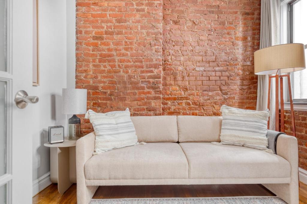 a living room with a brick wall and a couch at Hip E Village 2BR w WD nr L Train NYC-824 in New York